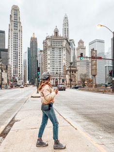 a woman is walking down the street with her cell phone in her hand and buildings behind her