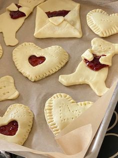 some heart shaped pastries sitting on top of a baking pan with jam in them