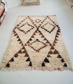 a white and brown rug sitting on top of a floor next to a book shelf