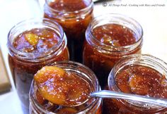 several jars filled with different kinds of food and one has a spoon sticking out of it