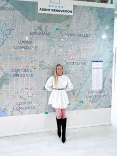 a woman standing in front of a map with her hands on her hips and wearing knee high boots