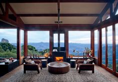 a living room filled with furniture and a fire place in front of large glass windows