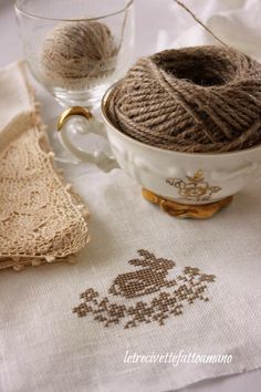 a white cup with some yarn in it next to a pair of glasses and a napkin