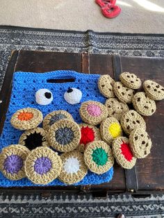 a crocheted blue bag with buttons and eyes on it sitting on top of a wooden table