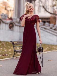 a woman in a long dress is walking down the street with her hand on her hip