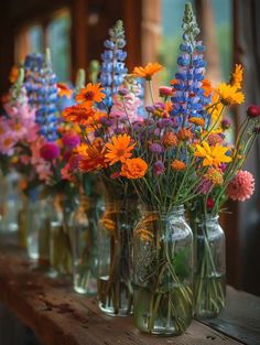 colorful wildflowers in mason jars lined up on a table