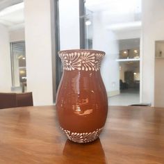 a brown vase sitting on top of a wooden table