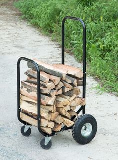 a hand truck filled with firewood sitting on top of a dirt road