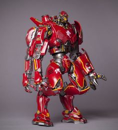 a red and yellow robot standing in front of a gray background