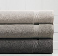 three towels stacked on top of each other in front of a white tiled bathroom wall