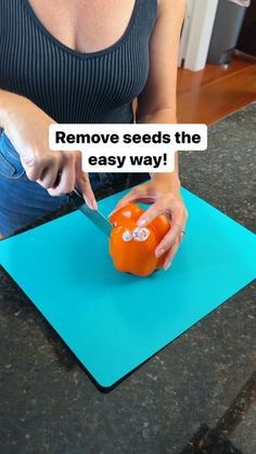 a woman cutting up an orange on top of a blue cutting board with a knife