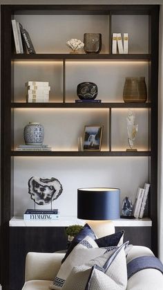 a living room filled with furniture and bookshelves next to a wall mounted lamp