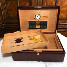 an open briefcase with tools in it sitting on a white blanket next to a clock