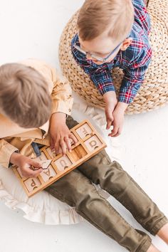 two young children playing with wooden letters on the floor