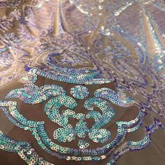 blue and silver sequins on fabric with an intricate design in the center,