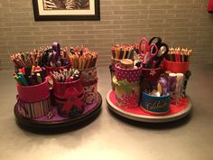 two cups with pens and pencils in them sitting on a counter next to each other