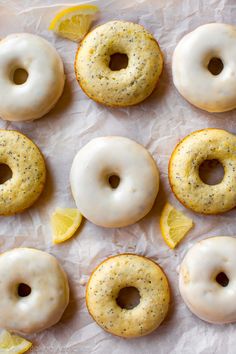 glazed donuts with lemon and poppy seeds arranged on wax paper next to slices of lemon