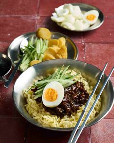 two bowls filled with noodles and an egg on top