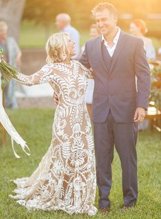 a man and woman standing next to each other on top of a lush green field