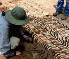 a man kneeling down in front of a pile of old tire tracks that have been laid on the ground