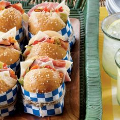 many sandwiches are wrapped in blue and white checkered paper on a tray next to drinks