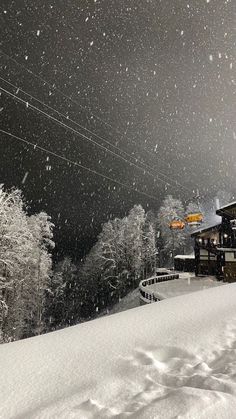 a snow covered ski slope with power lines above it and trees on the other side