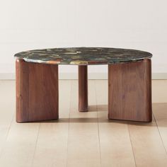 a table made out of wood and marble on the floor in front of a white wall