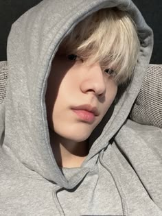 a boy with blonde hair wearing a grey hoodie and looking at his cell phone