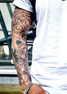 a man with a tattoo on his arm holding a skateboard in front of him