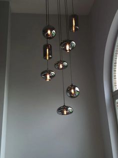 a chandelier hanging from the ceiling in front of a window with round glass shades