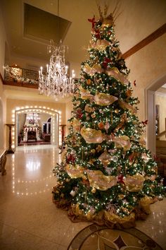 a decorated christmas tree in the middle of a room with chandelier and chandeliers