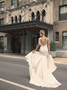 a woman in a white dress is walking down the street with her back to the camera