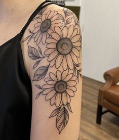 a woman with a tattoo on her arm has sunflowers and leaves tattooed on it