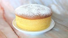 a yellow cake sitting on top of a white plate next to a cupcake covered in powdered sugar