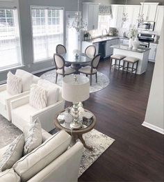 a living room filled with furniture next to a kitchen and dining room table covered in white pillows