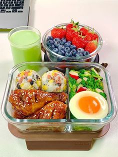 two plastic containers filled with food next to a cup of green juice and strawberries