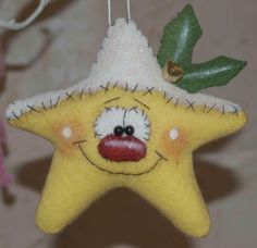 a yellow felt star ornament with a red nose and green leaf on it