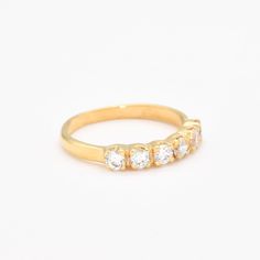 a yellow gold ring with five diamonds on the top and bottom, set against a white background