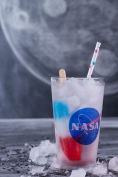 a glass filled with ice and two straws sitting on top of an icy surface