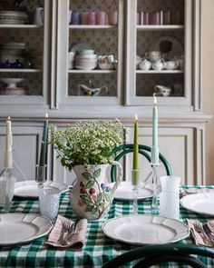 the table is set with plates, silverware and flowers in a vase on it