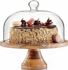 a cake under a glass dome on top of a wooden stand