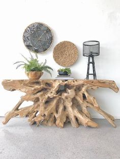 a table made out of driftwood with plants on top and two wall hangings above it