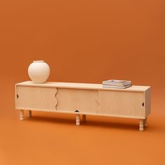 a white vase sitting on top of a wooden cabinet next to a stack of books