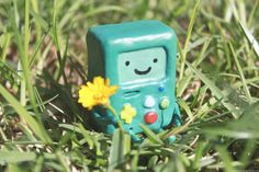 a small toy with a flower in it's mouth sitting in the grass,