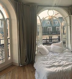 a large bed sitting inside of a bedroom next to an arched window with lots of windows