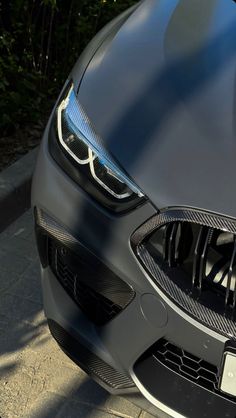 the front end of a black car parked on a sidewalk