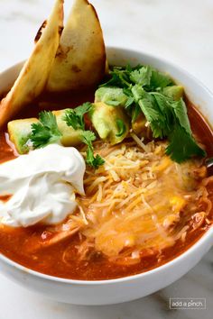 a bowl of soup with tortilla chips and sour cream on the side is ready to be eaten