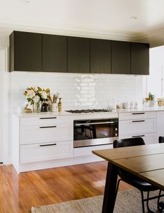 a kitchen with black and white cabinets, wood flooring and a stove top oven