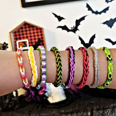 several different colored bracelets on someone's arm in front of a halloween background