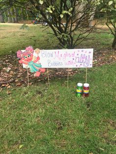 a sign that is on the grass with some paint cans in front of it and another sign behind it